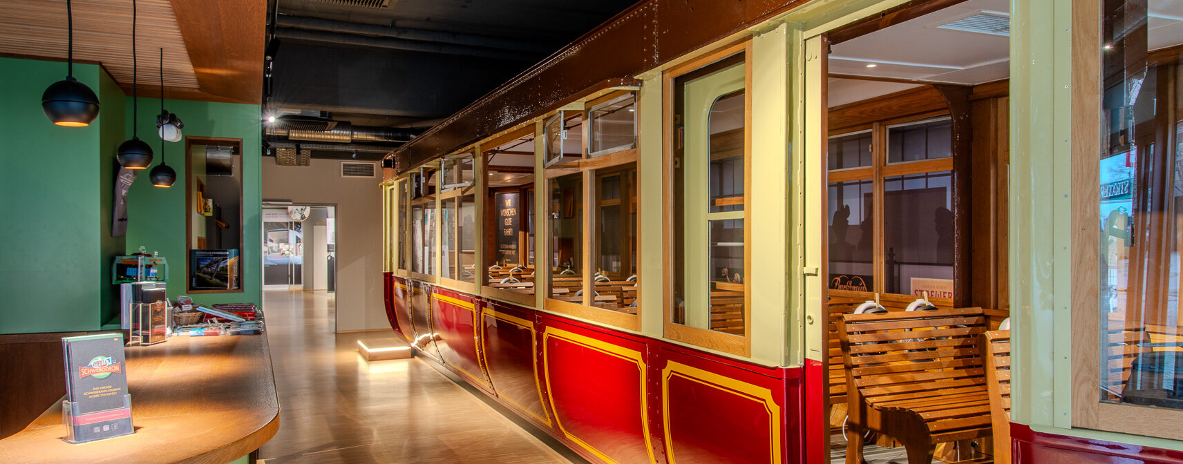A restaurant interior featuring a vintage red and yellow train car with wooden seats, integrated into the dining area. Modern decor and lighting complement the unique setting.